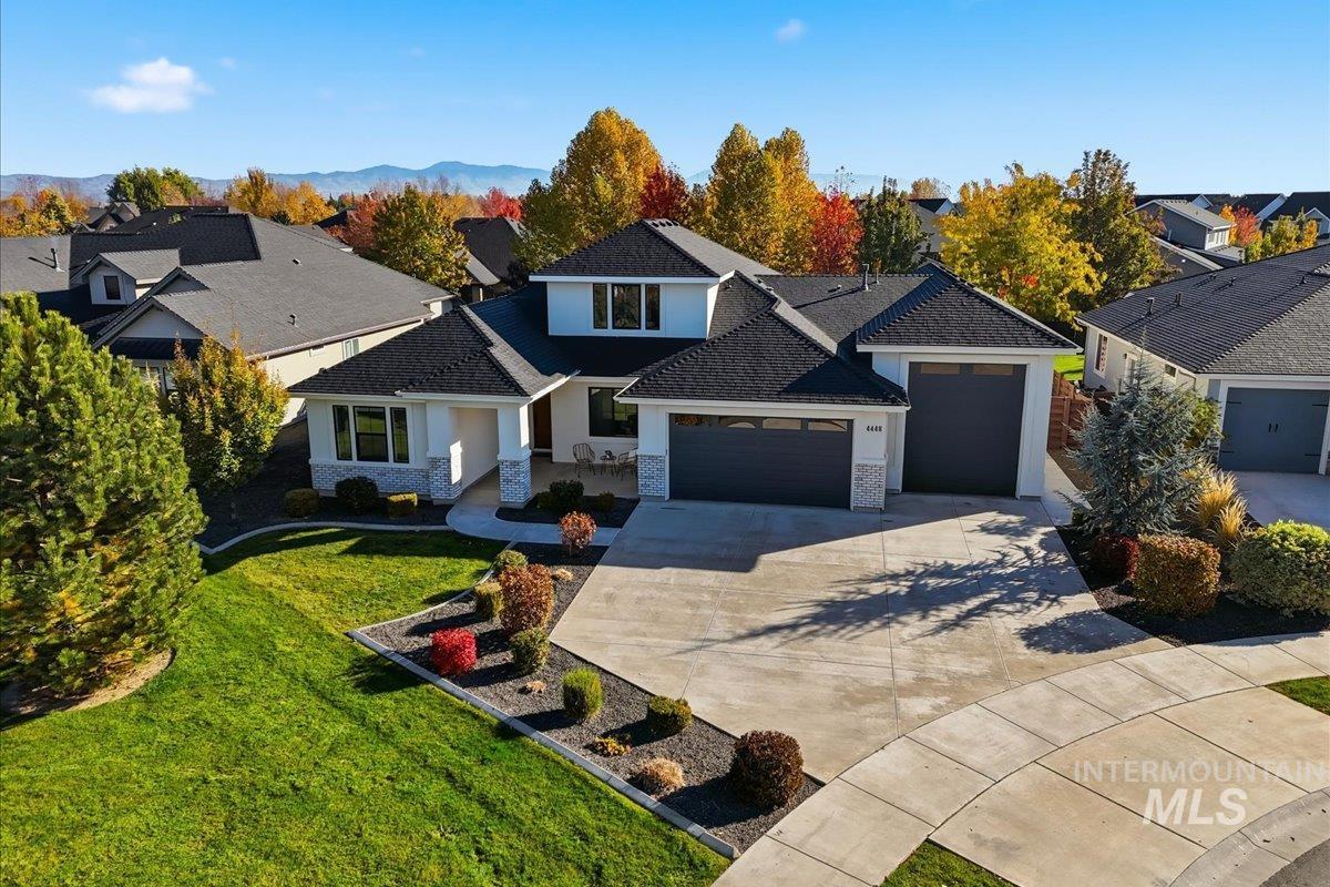 Traditional home with a garage, a front yard, a residential view, and driveway