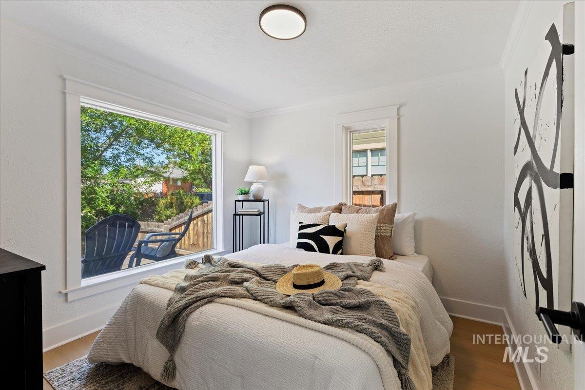 Bedroom with crown molding, wood finished floors, and a textured ceiling