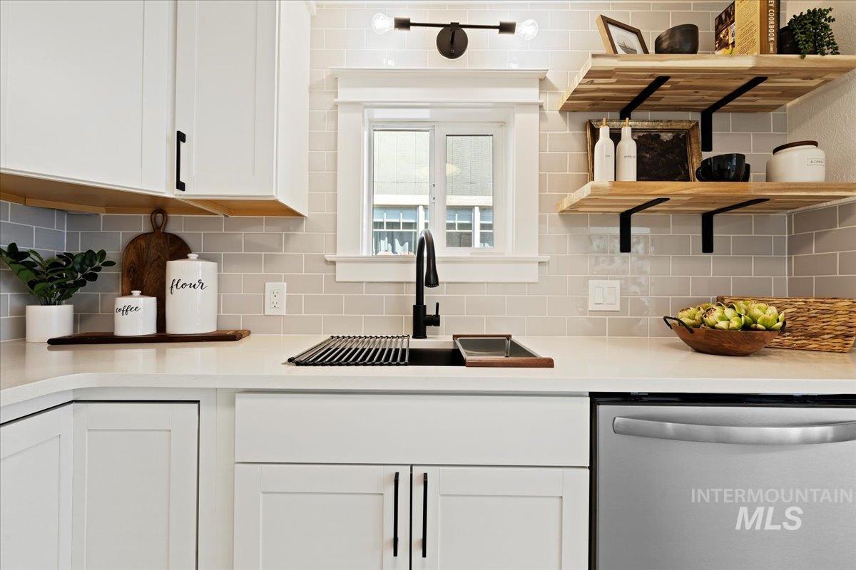 Kitchen with dishwasher, white cabinets, open shelves, and tasteful backsplash