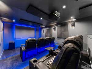 Dedicated home theater featuring a large projection screen, recessed ceiling lighting, and blue accent lighting