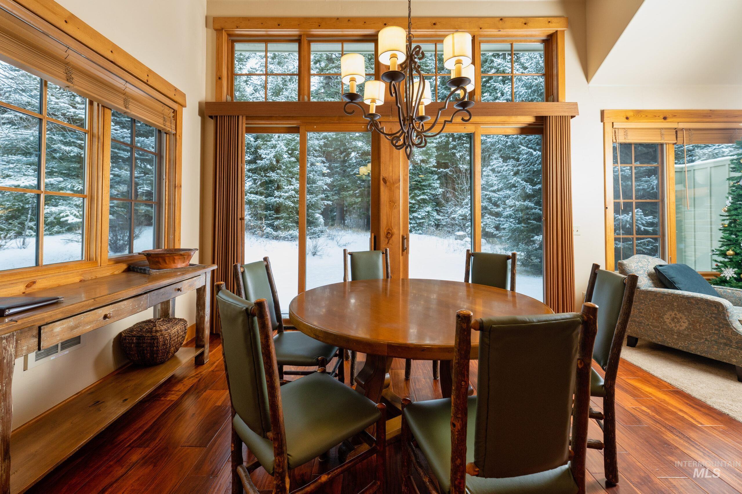 Dining room with a chandelier, dark wood-style flooring, and healthy amount of natural light