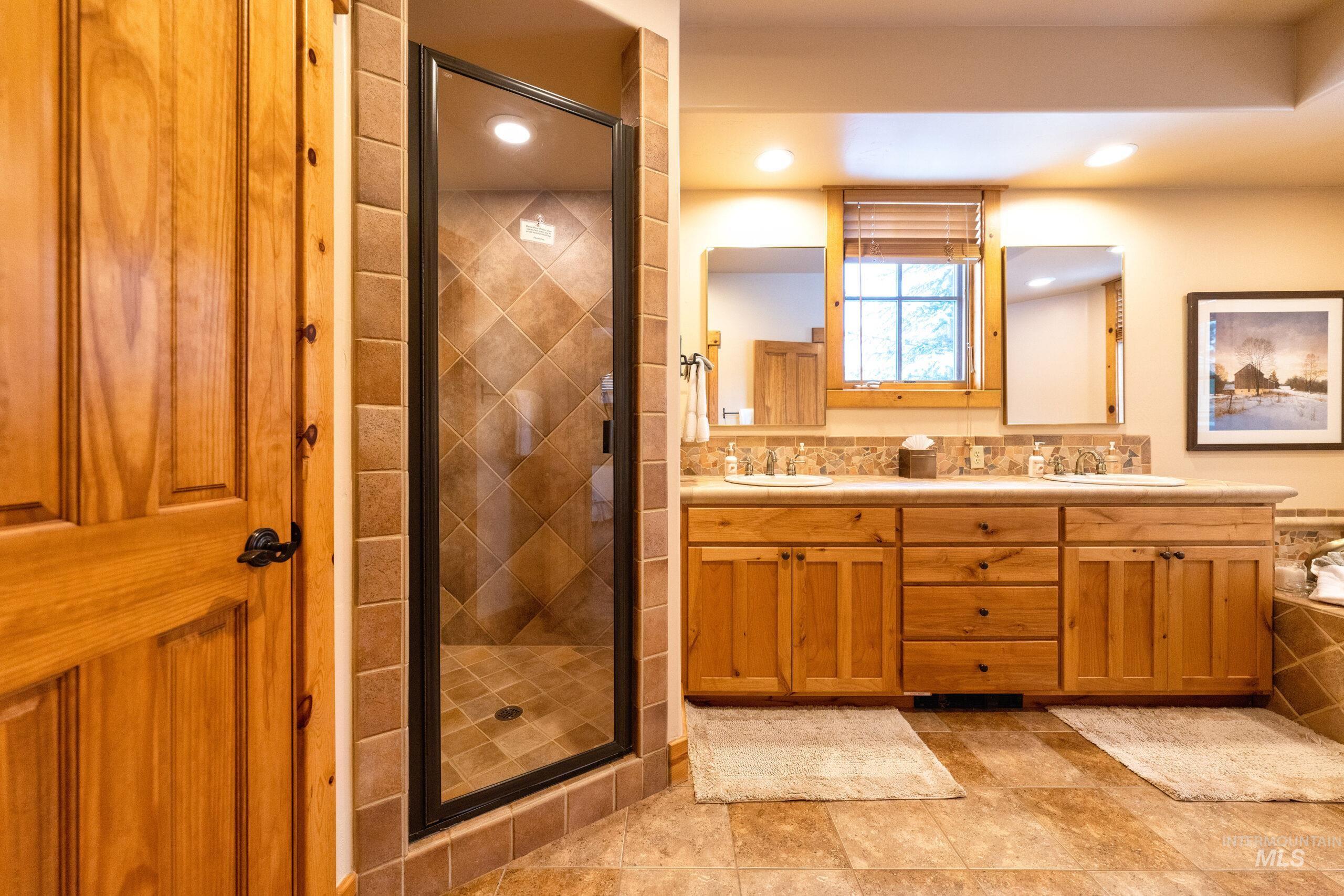 Full bathroom featuring double vanity and a stall shower