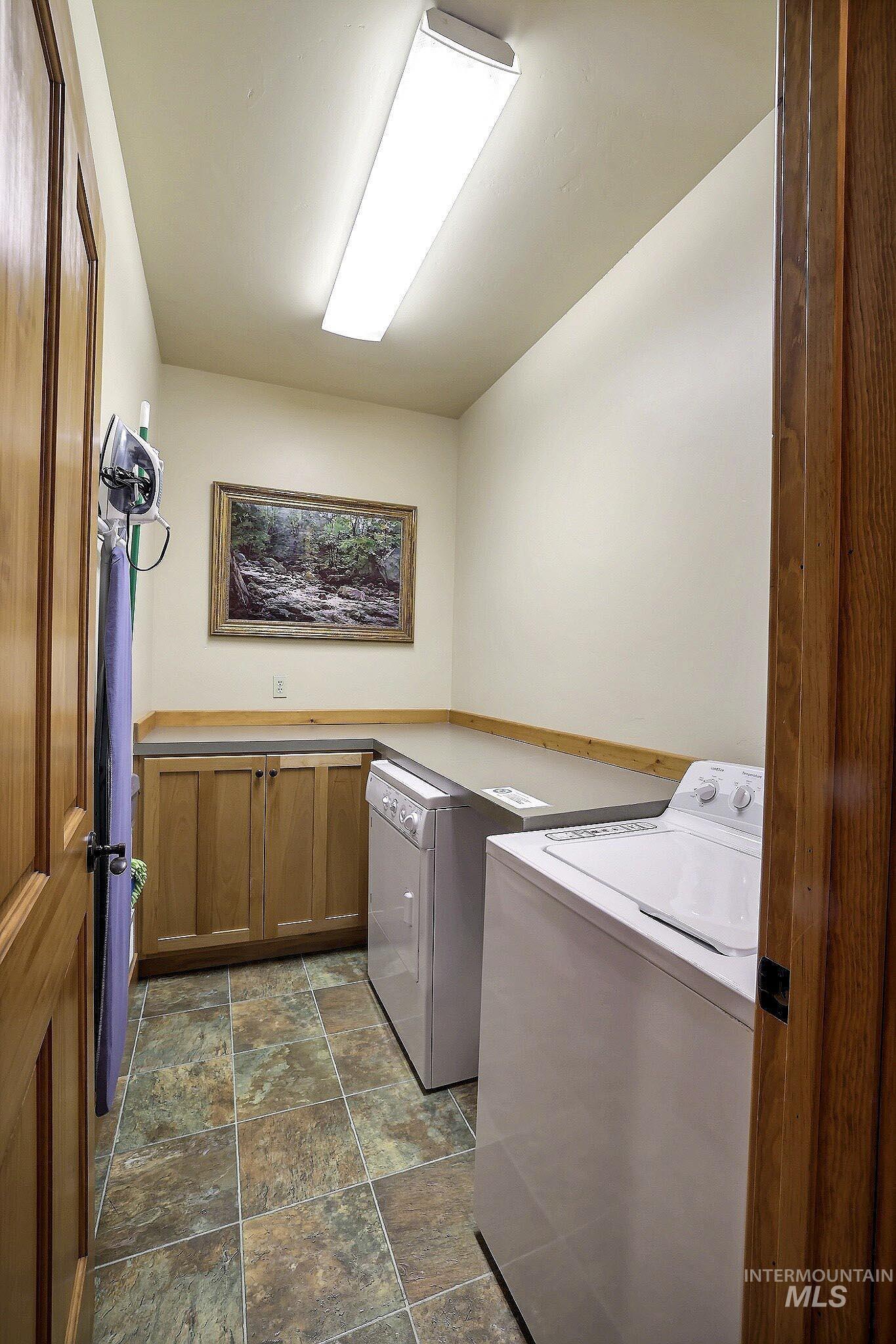 Laundry room with stone finish flooring and independent washer and dryer