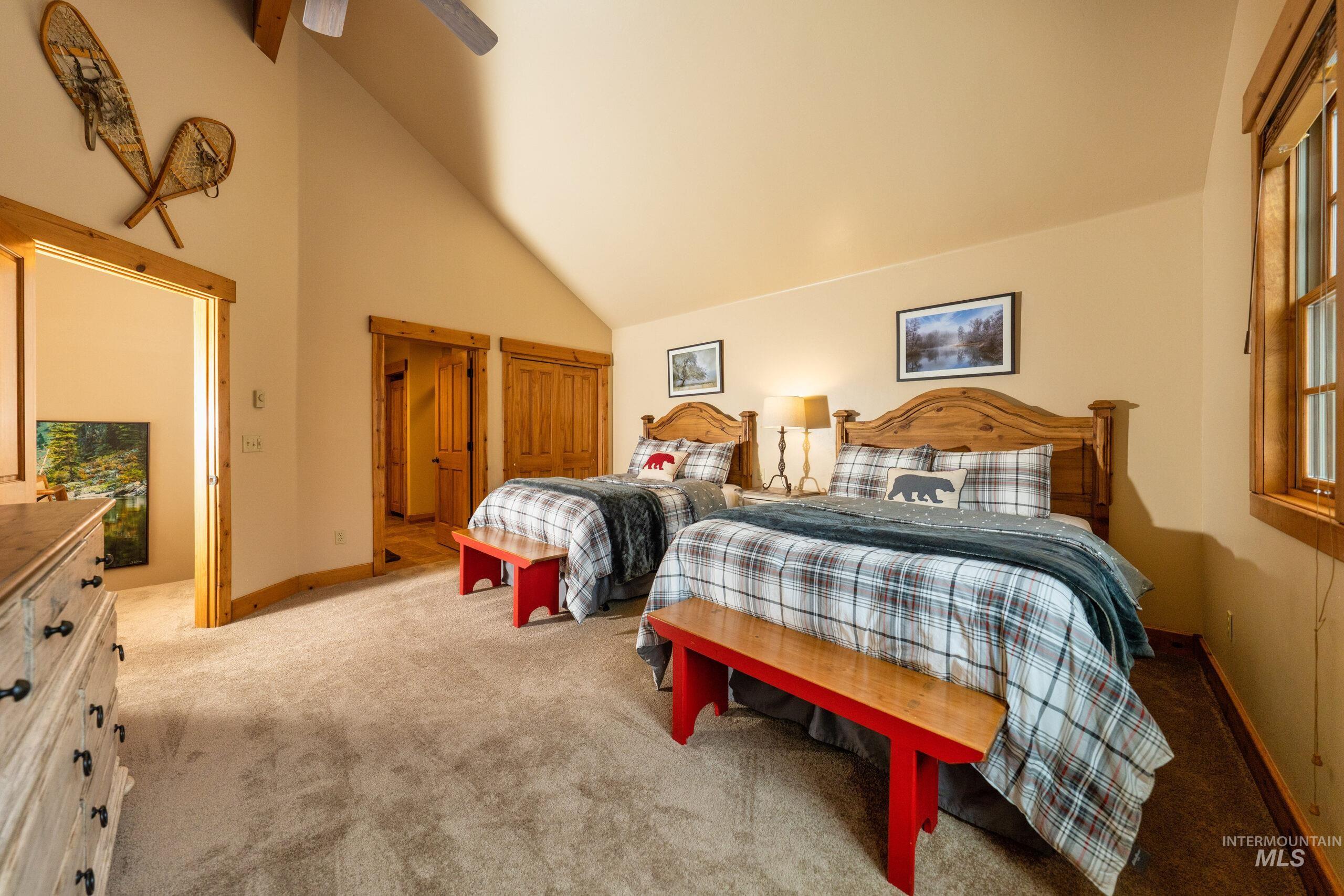Bedroom featuring high vaulted ceiling, light carpet, and ceiling fan