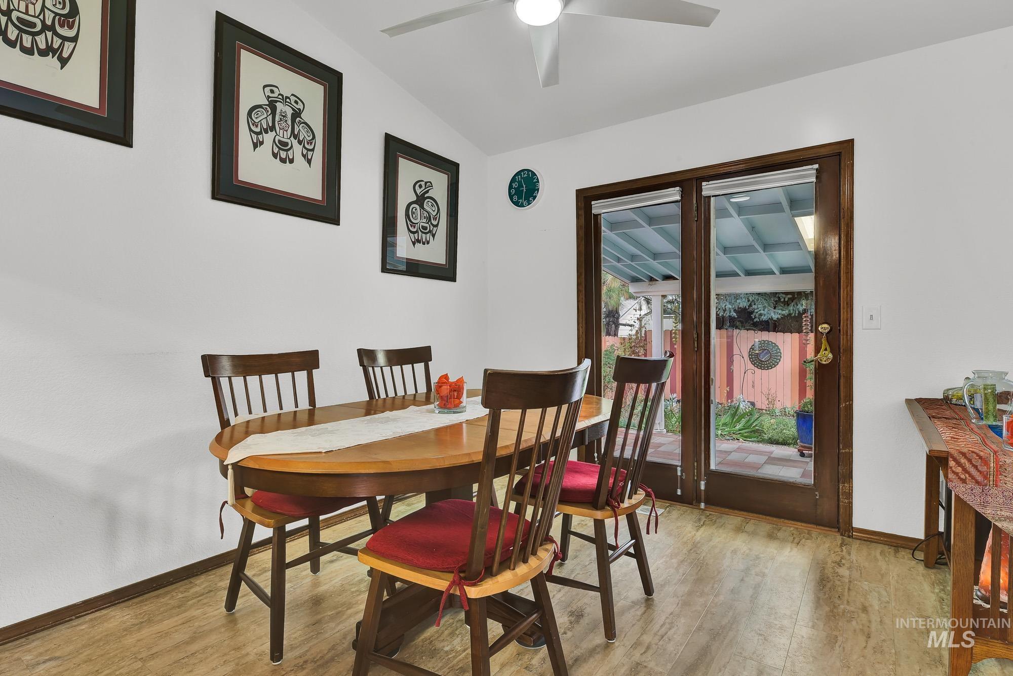 Dining space featuring light wood-type flooring, vaulted ceiling, and ceiling fan