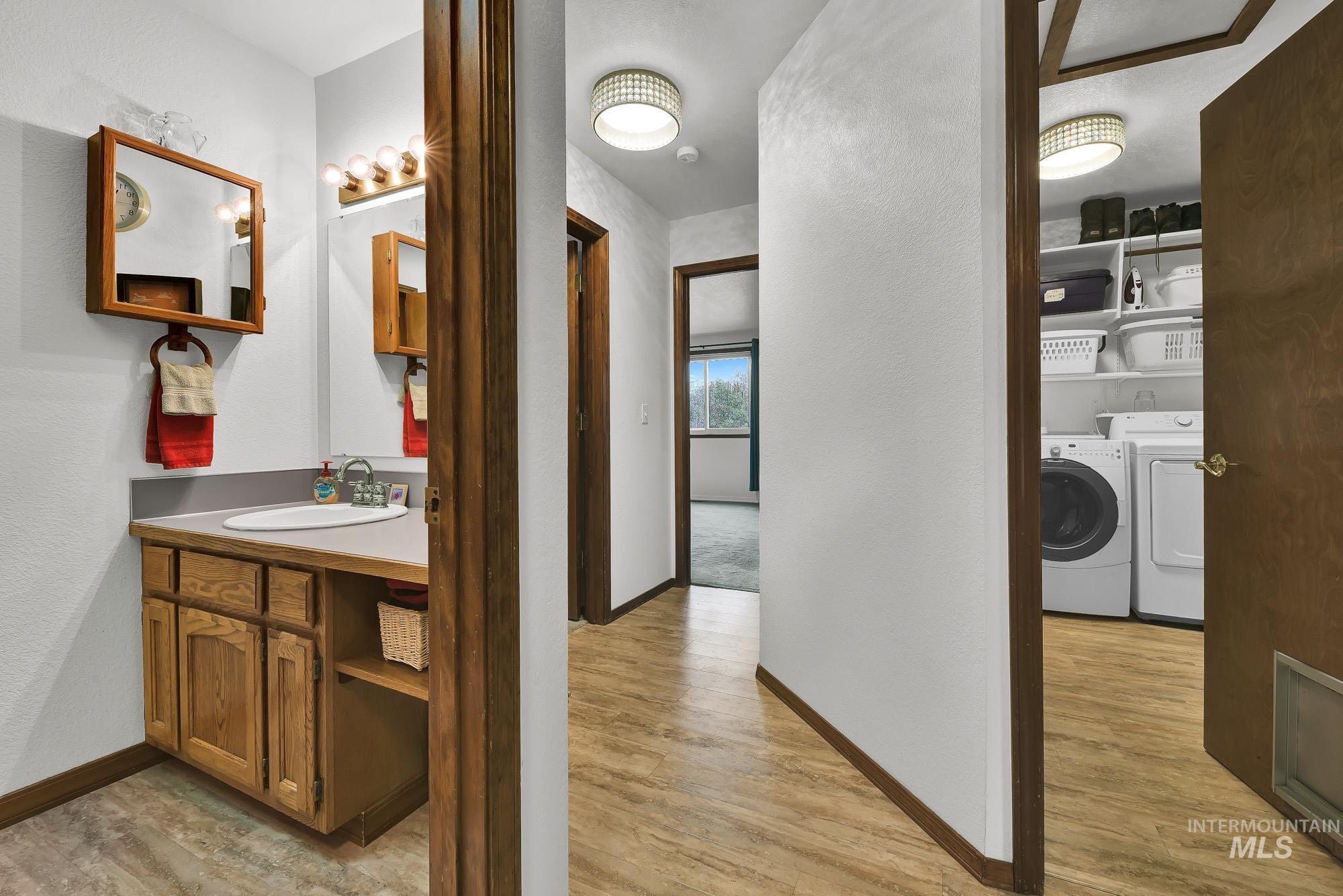 Bathroom featuring light wood finished floors, a textured wall, washer and dryer, and vanity