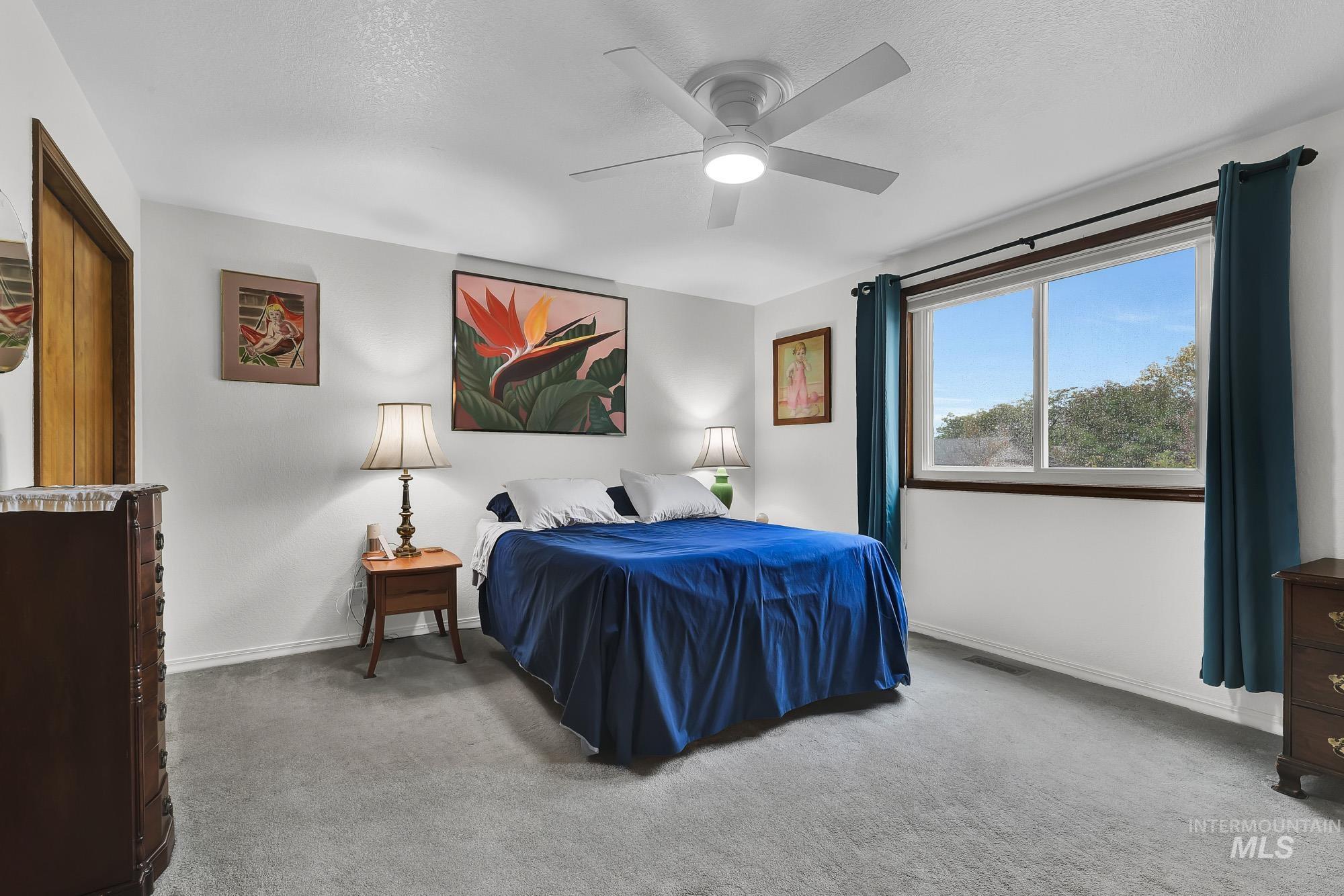 Bedroom with light carpet, a ceiling fan, and a textured ceiling