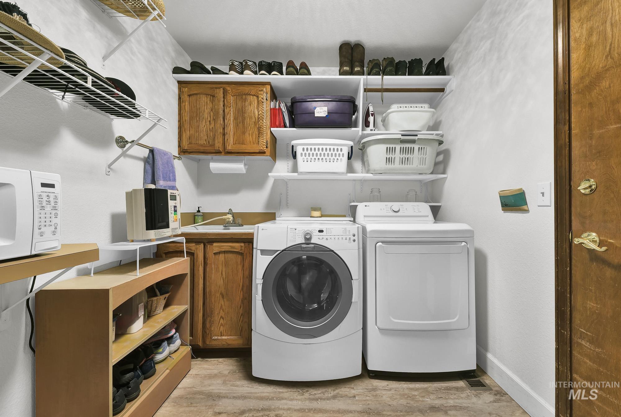 Laundry area featuring light wood-style floors, cabinet space, and washing machine and dryer
