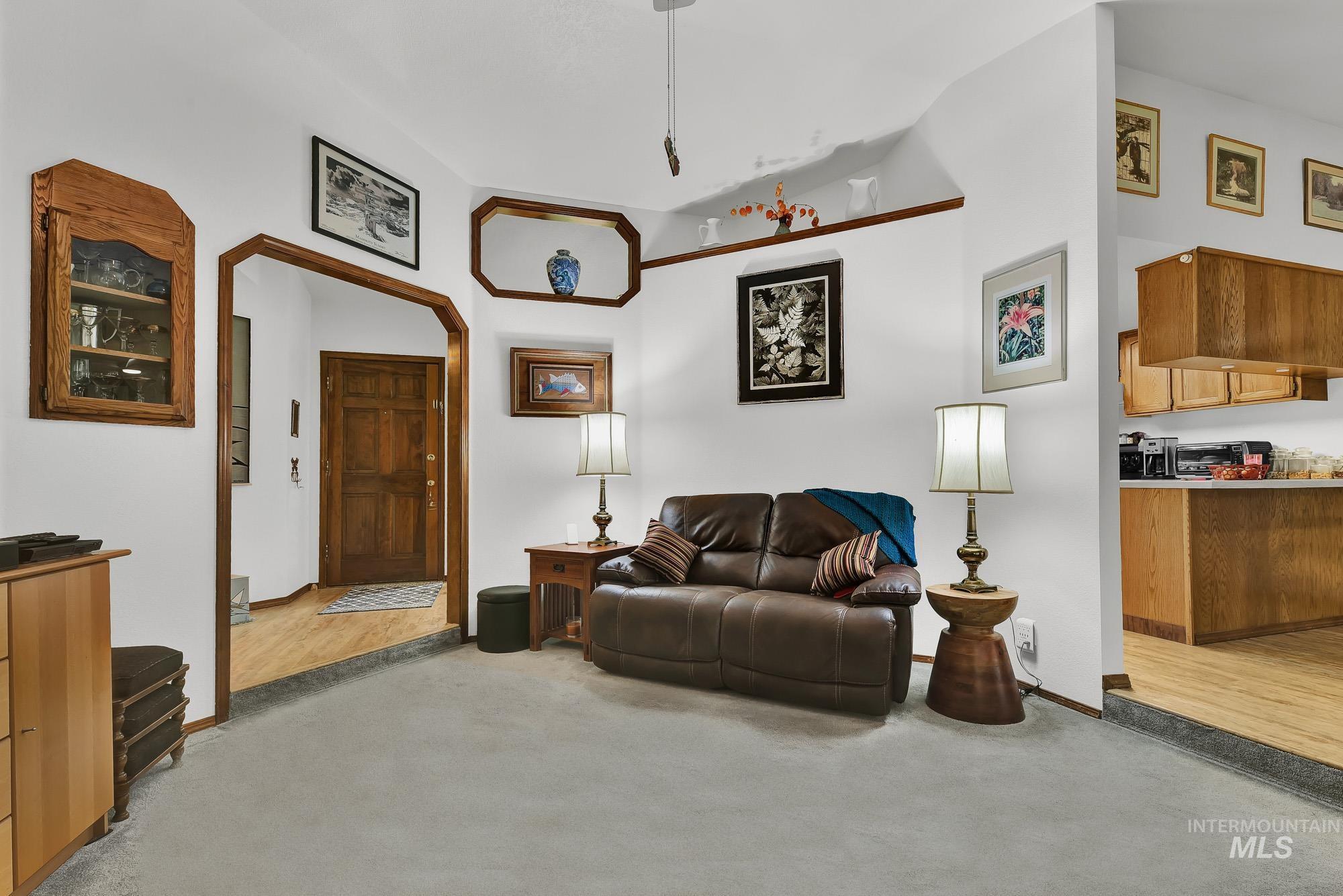 Living area featuring arched walkways, light carpet, and lofted ceiling