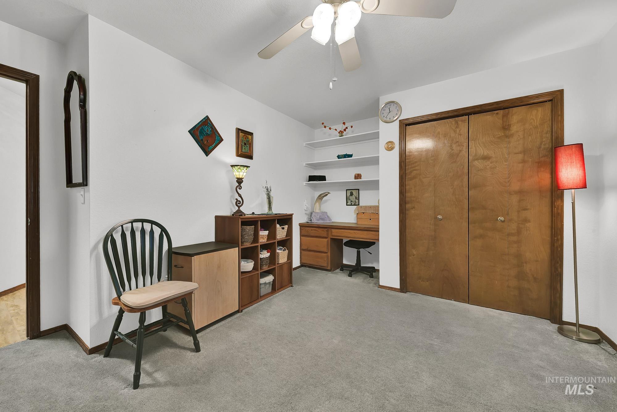 Sitting room with ceiling fan, light colored carpet, and a desk