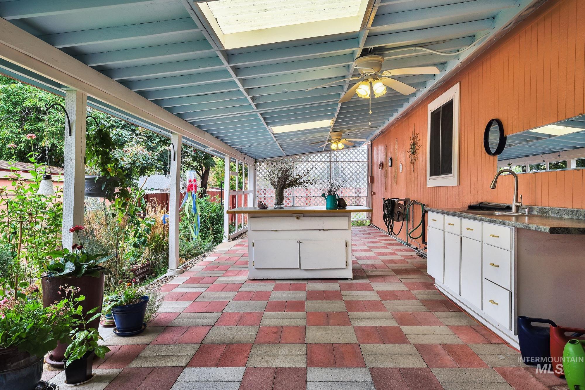 Fenced backyard with a patio, ceiling fan, and exterior kitchen
