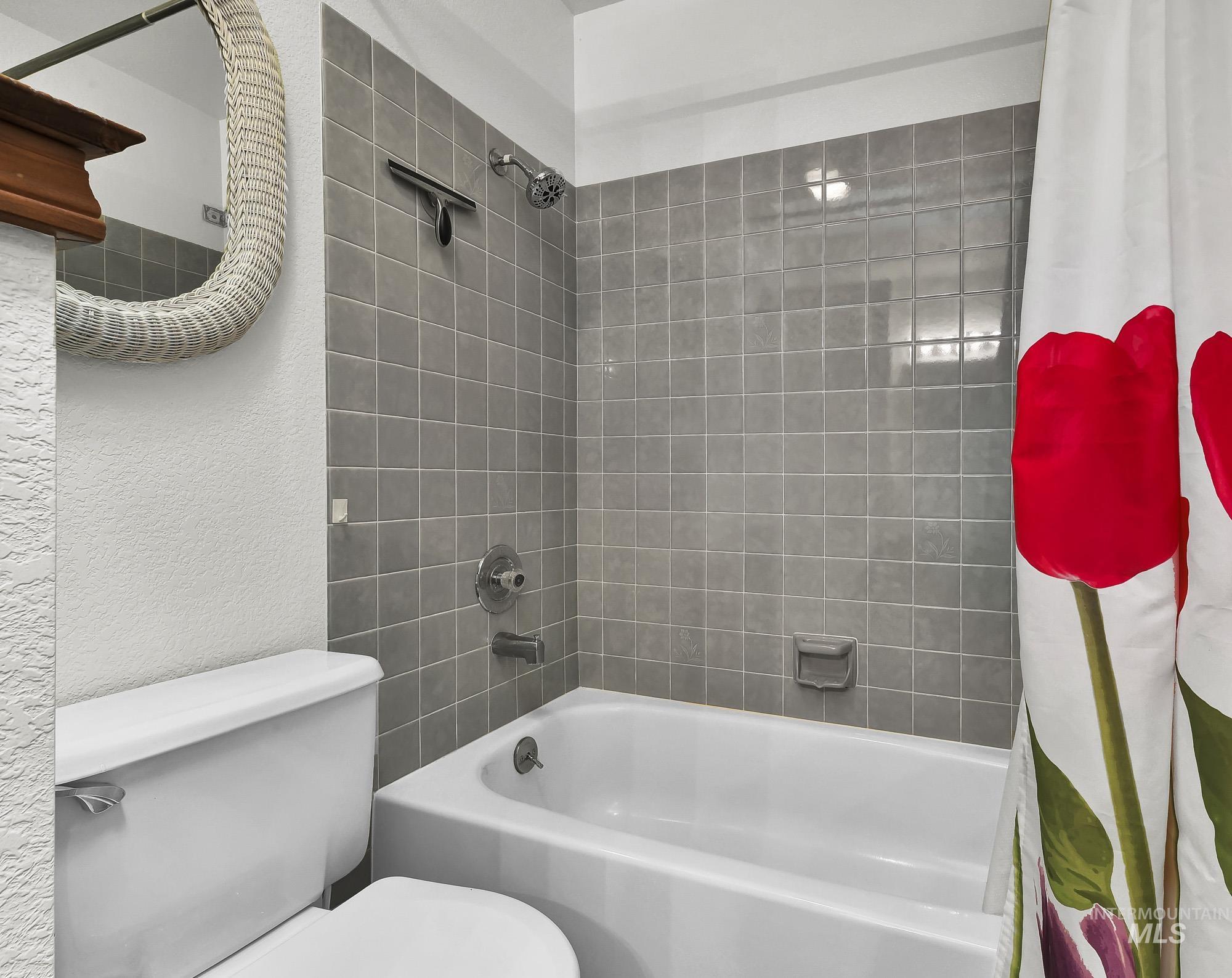Bathroom with shower / bath combo and a textured wall
