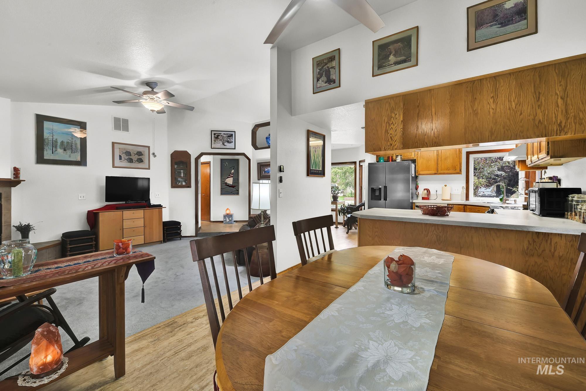 Dining area with arched walkways, plenty of natural light, ceiling fan, light wood finished floors, and a towering ceiling