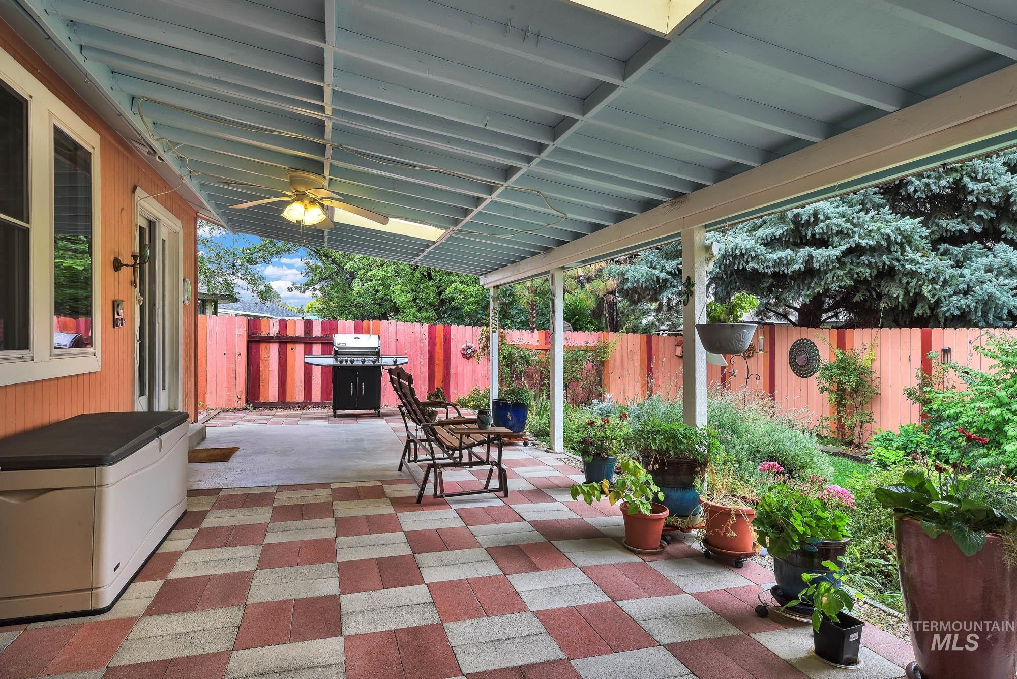 Fenced backyard with a patio, a grill, and a ceiling fan