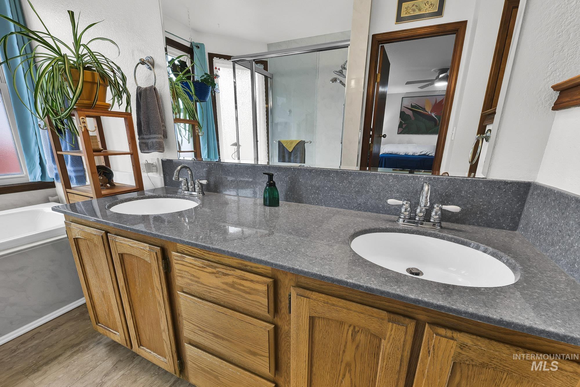 Ensuite bathroom featuring a stall shower, double vanity, a bath, and light wood-style flooring