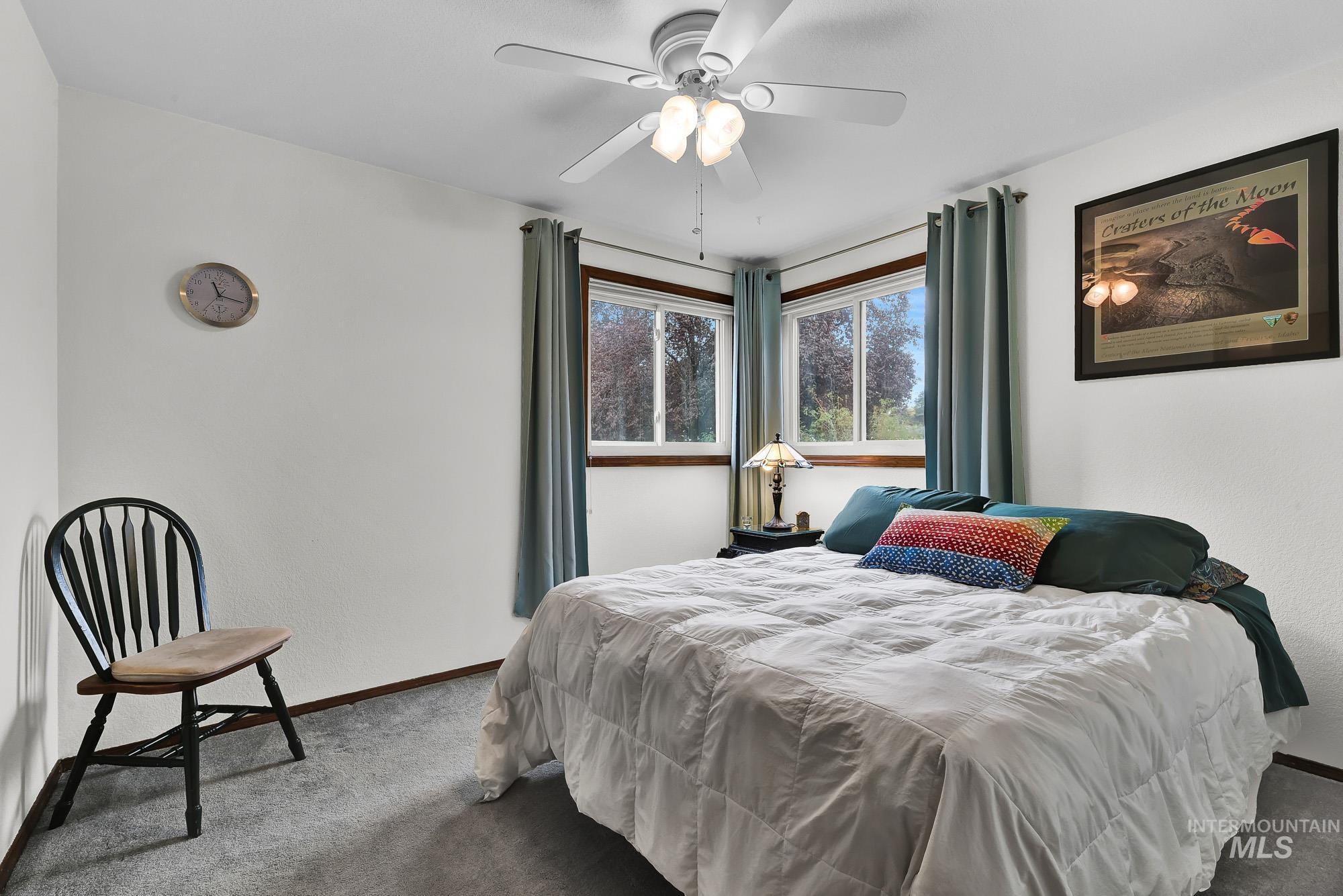 Carpeted bedroom featuring a ceiling fan and a textured wall
