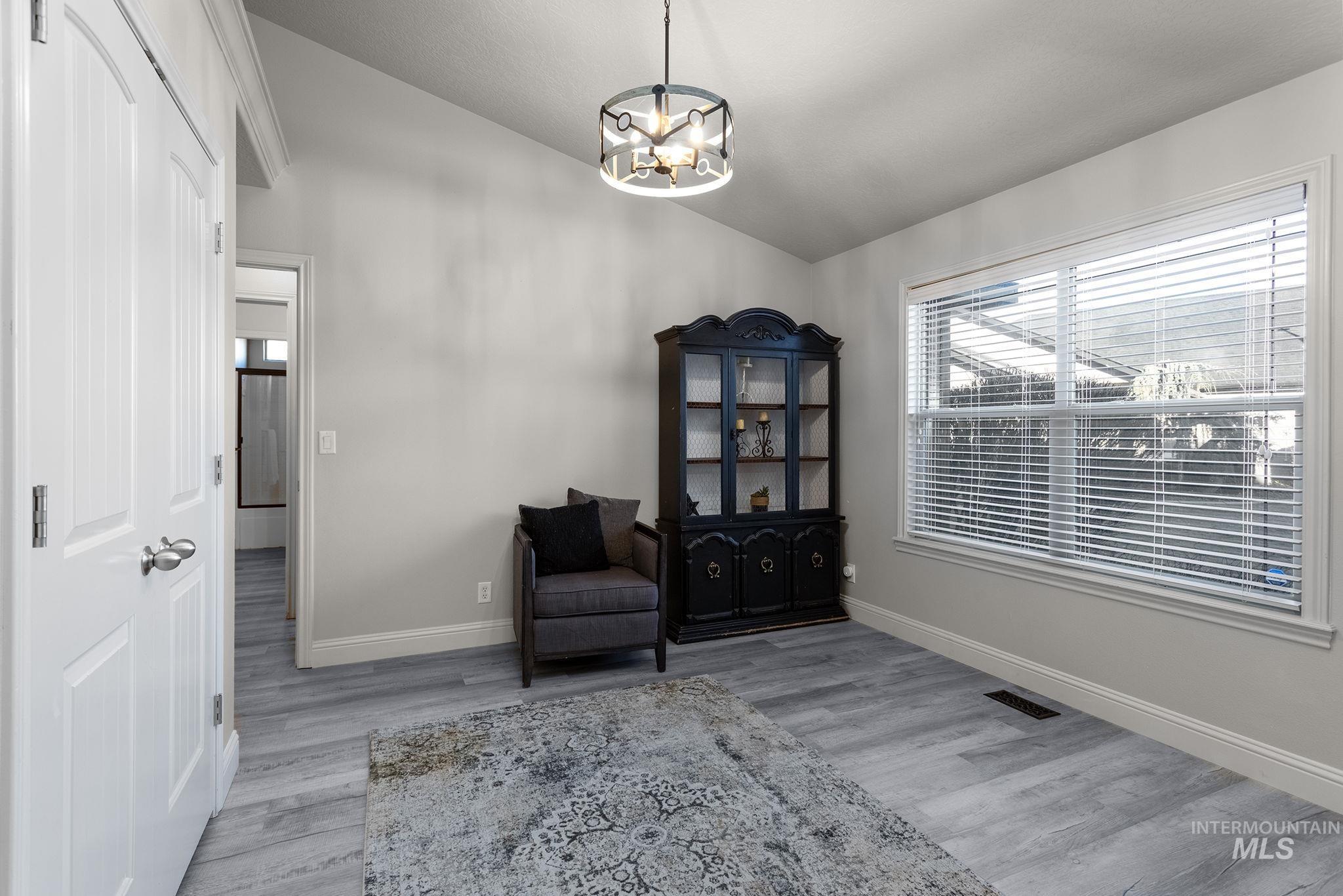 Sitting room with lofted ceiling, light wood finished floors, and a chandelier