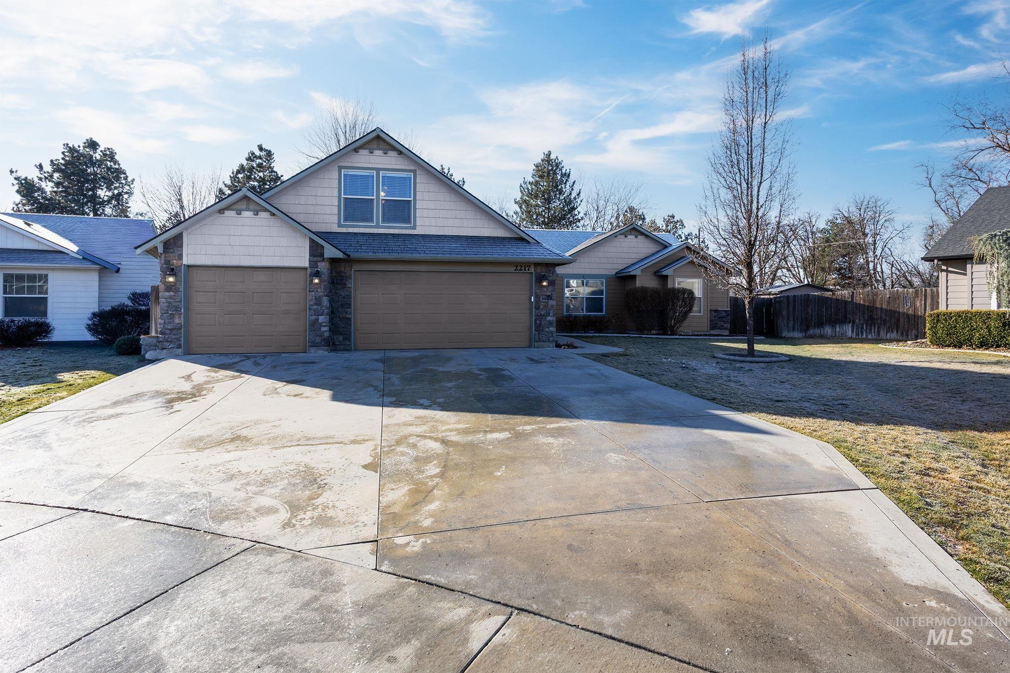 Craftsman-style house featuring driveway and stone siding