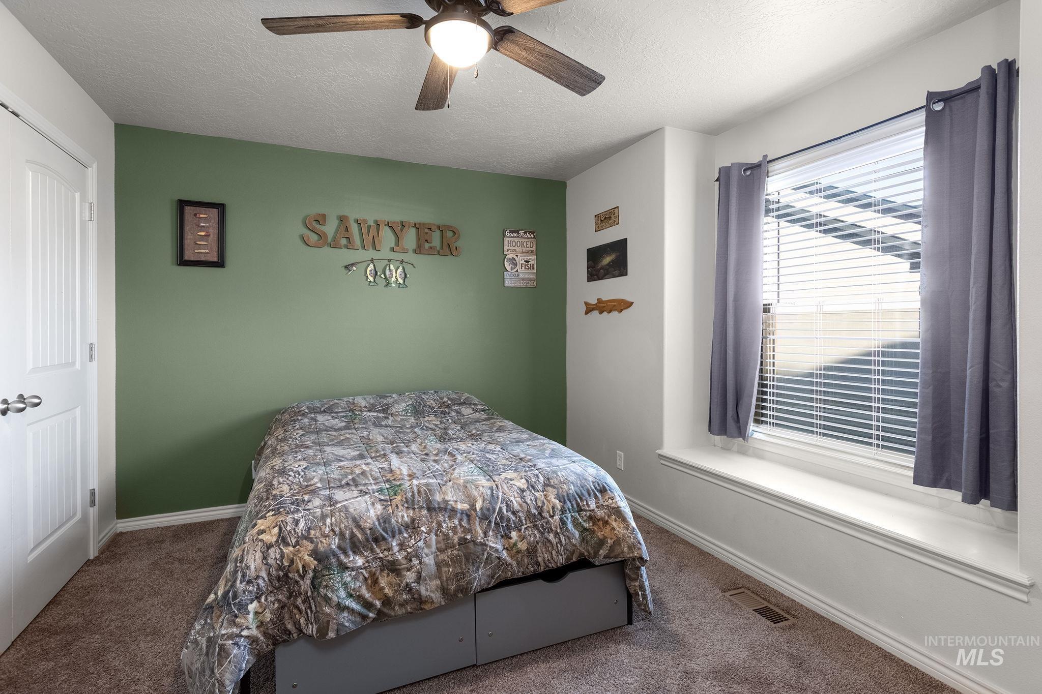 Bedroom with carpet flooring, a textured ceiling, and a ceiling fan