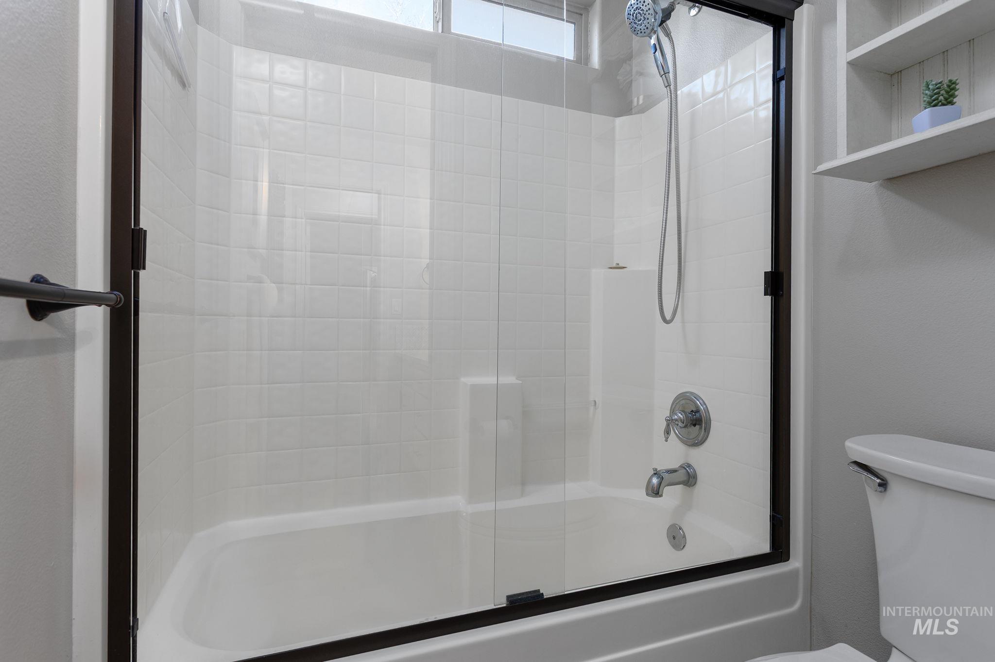 Full bathroom with bath / shower combo with glass door and toilet