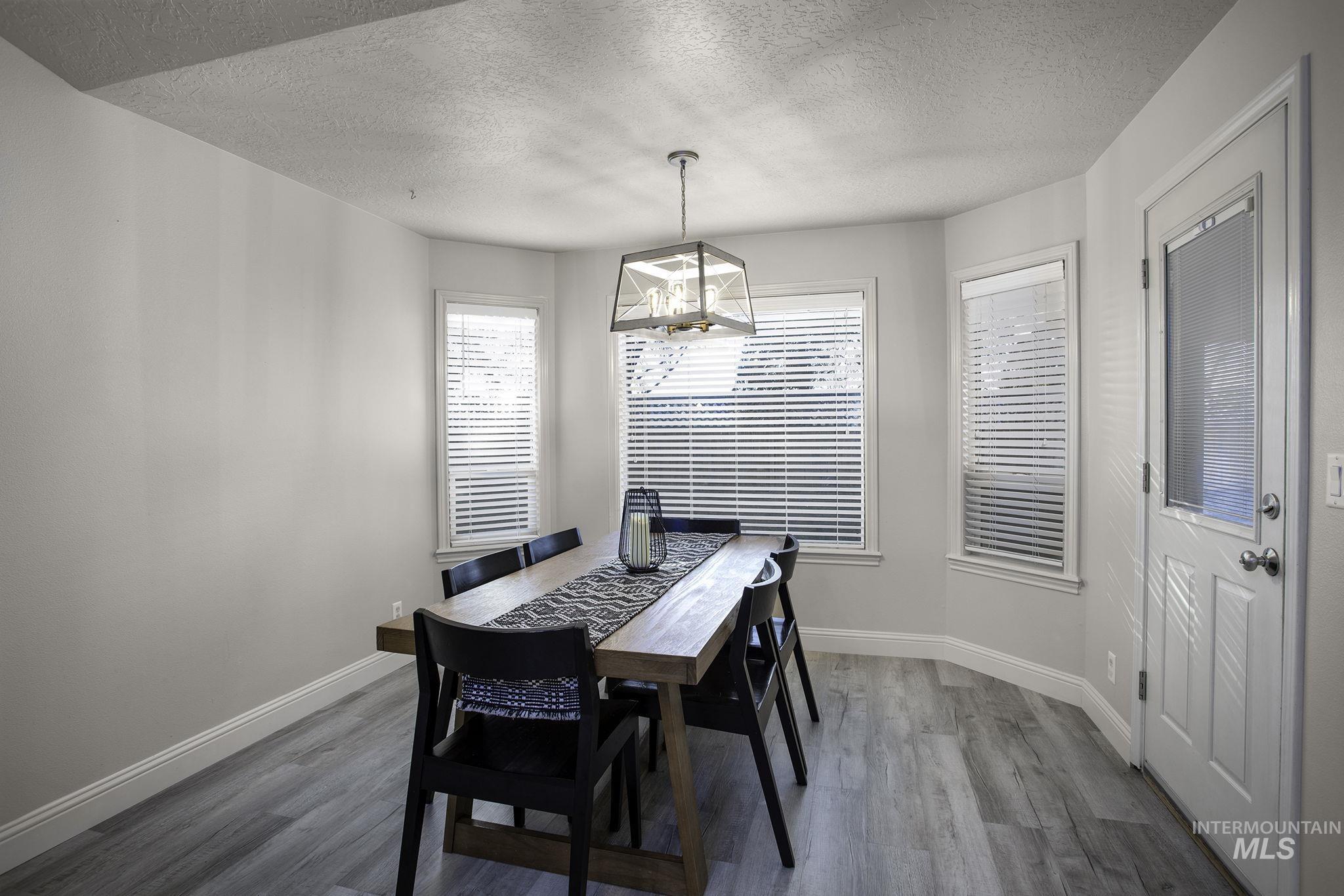 Dining space with dark wood finished floors, plenty of natural light, a textured ceiling, and a chandelier
