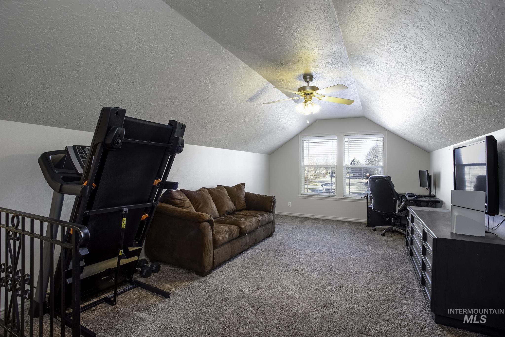Office featuring carpet floors, lofted ceiling, a ceiling fan, and a textured ceiling