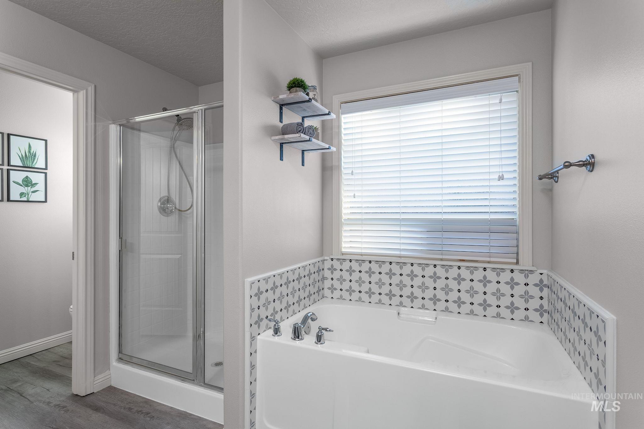 Bathroom featuring a shower stall, a bath, and a textured ceiling