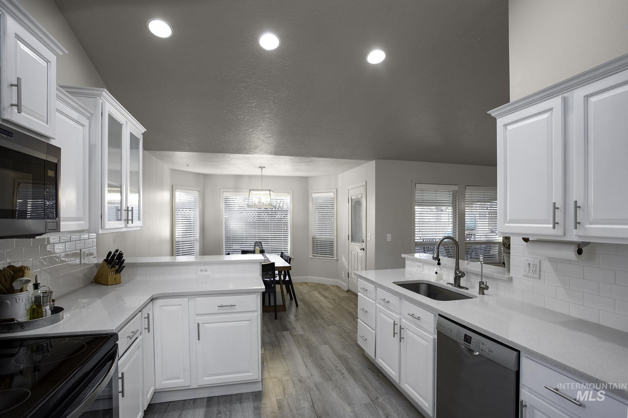Kitchen featuring a peninsula, decorative backsplash, light stone counters, stainless steel appliances, and recessed lighting