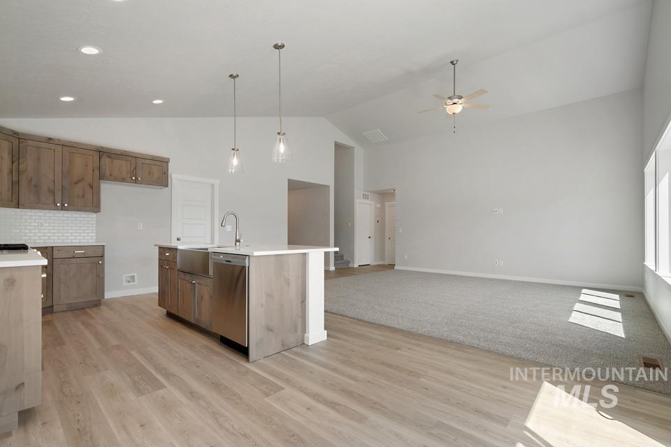 Kitchen featuring vaulted ceiling, light countertops, light wood-style flooring, dishwasher, and ceiling fan