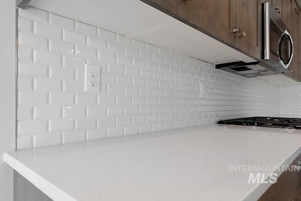 Kitchen featuring decorative backsplash, light countertops, and stainless steel appliances