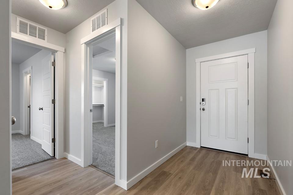 Hallway featuring light wood-style flooring and a textured ceiling