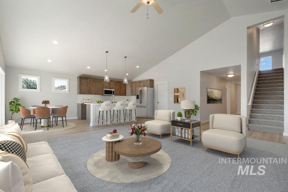 Living room with light wood-style floors, stairway, high vaulted ceiling, and ceiling fan