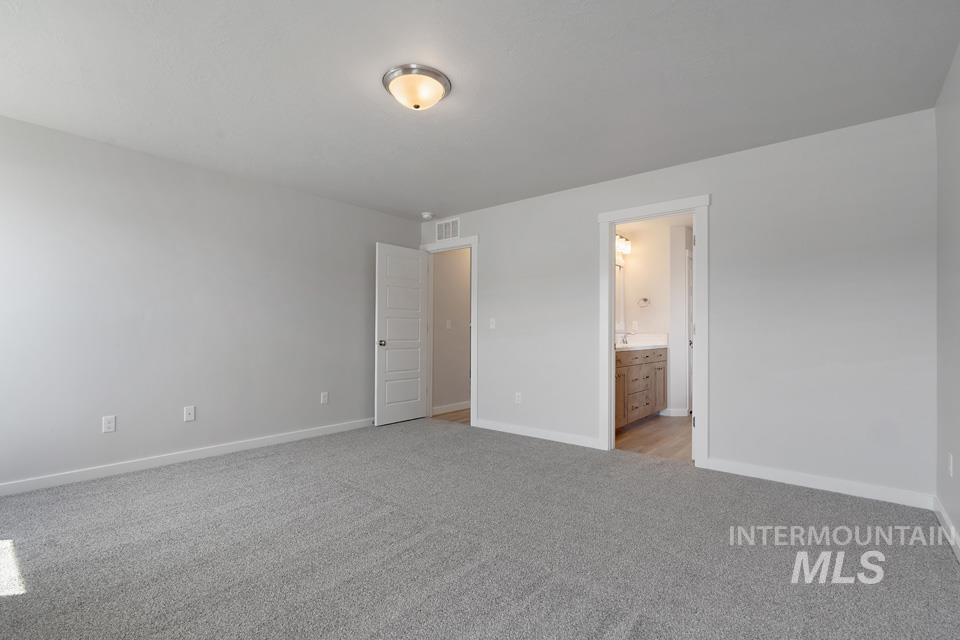 Unfurnished bedroom featuring light colored carpet and connected bathroom