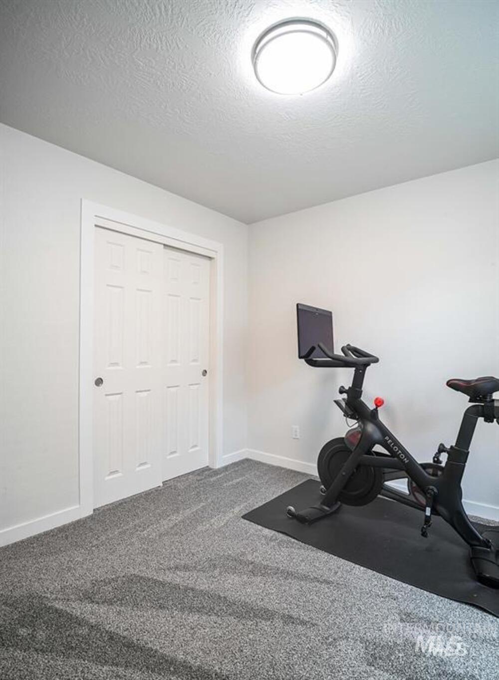 Exercise area featuring dark colored carpet and a textured ceiling