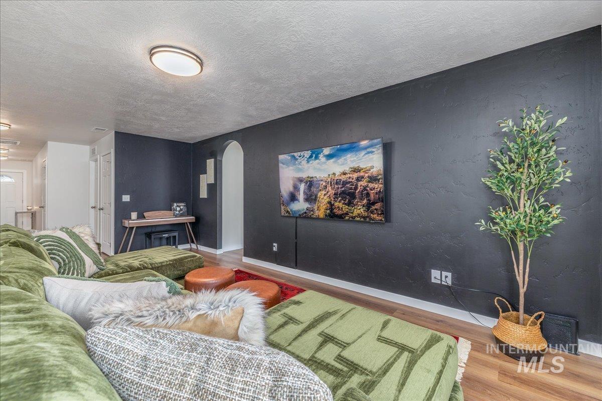 Living room with arched walkways, wood finished floors, and a textured ceiling