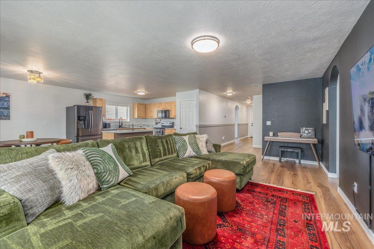 Living room featuring light wood finished floors, arched walkways, and a textured ceiling