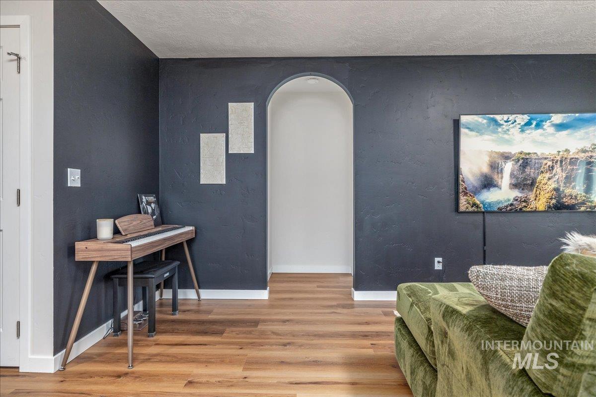 Living area featuring light wood-style flooring, arched walkways, and a textured ceiling