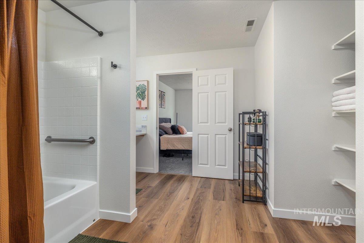 Ensuite bathroom featuring shower / tub combo and light wood-style floors