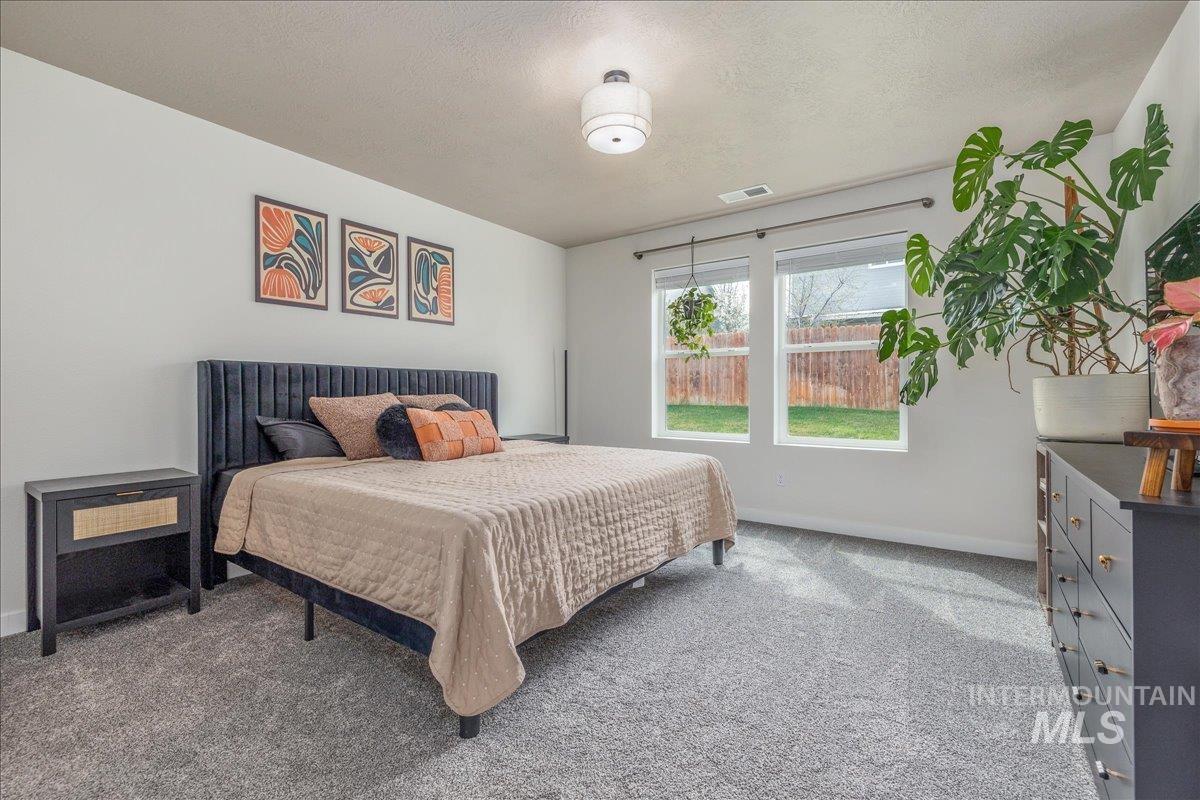 Carpeted bedroom with a textured ceiling and baseboards