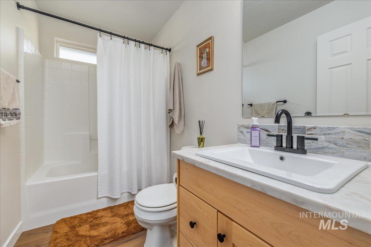 Bathroom featuring shower / bath combination with curtain, vanity, and light wood-style floors