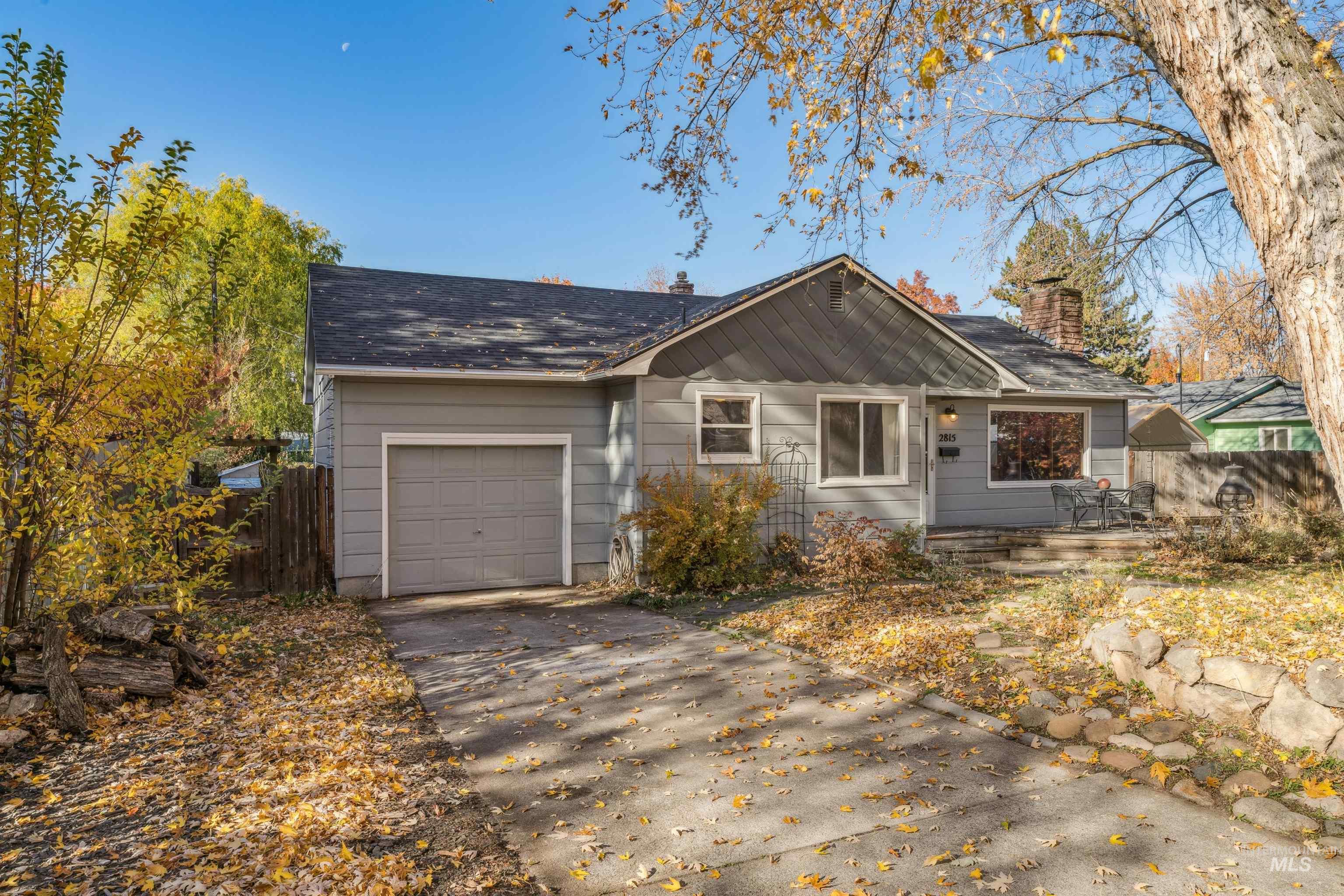 View of front of house with a chimney, driveway, an attached garage, and roof with shingles
