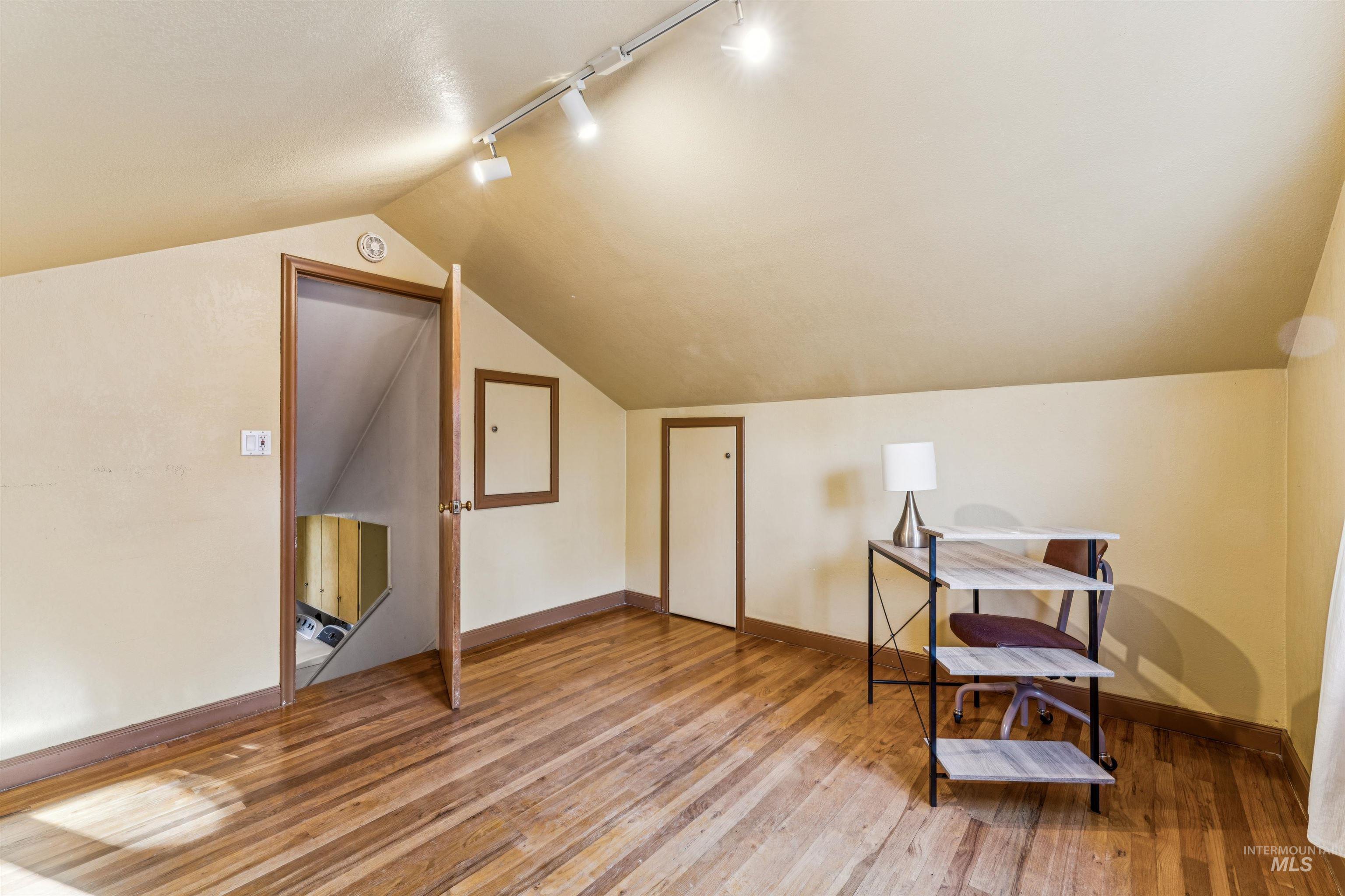 Office area featuring track lighting, light wood-style floors, and lofted ceiling
