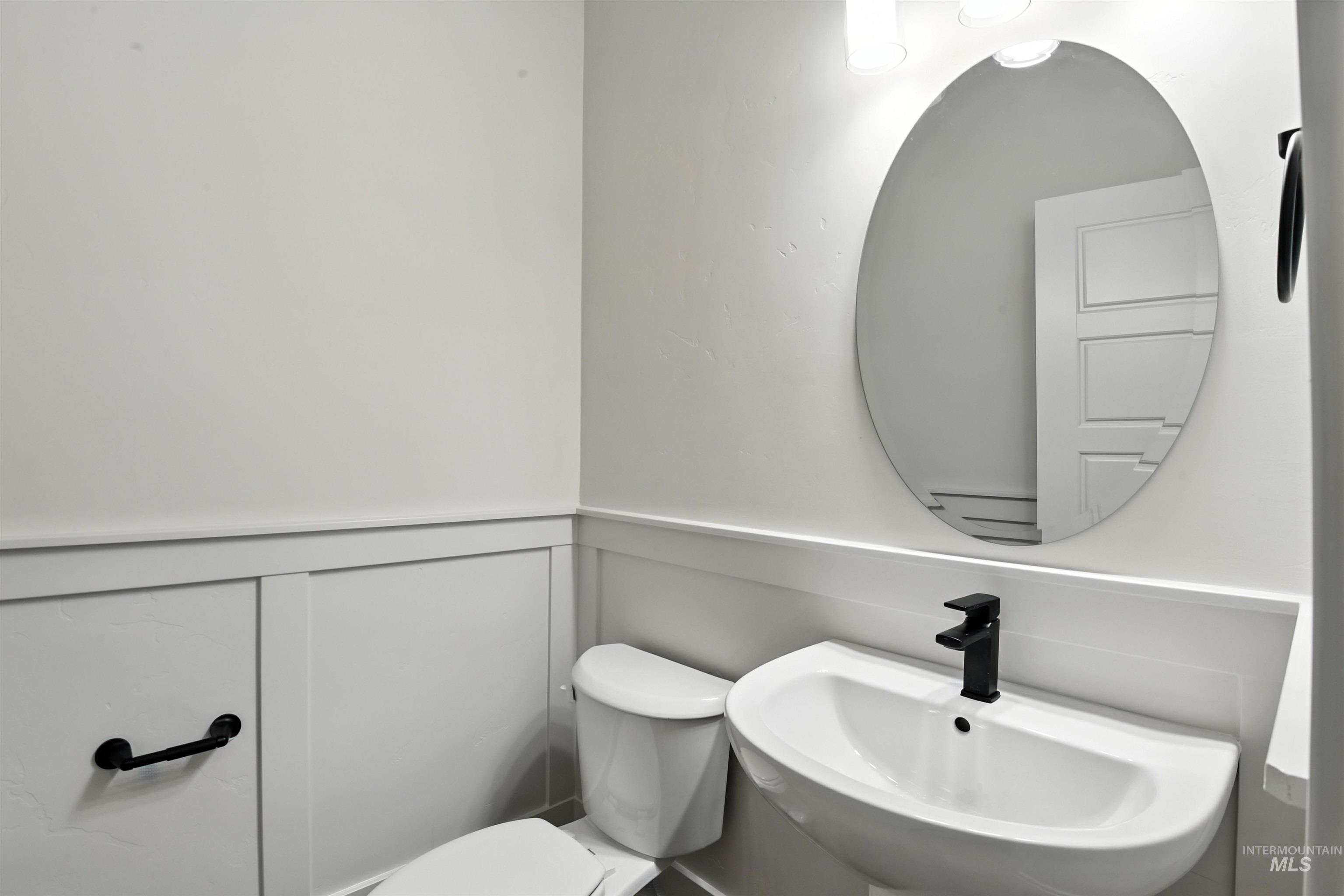 Half bath featuring toilet and a wainscoted wall