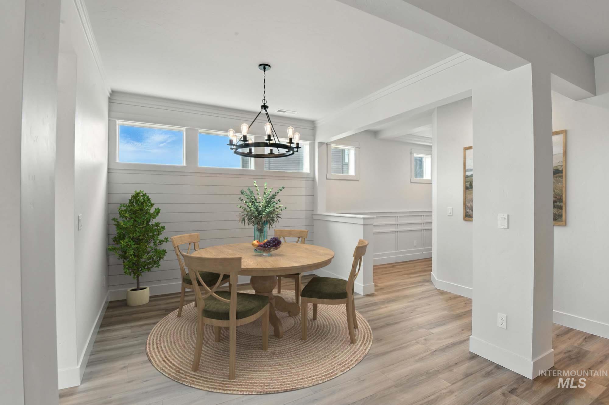Dining area with a chandelier, light wood-type flooring, plenty of natural light, and ornamental molding