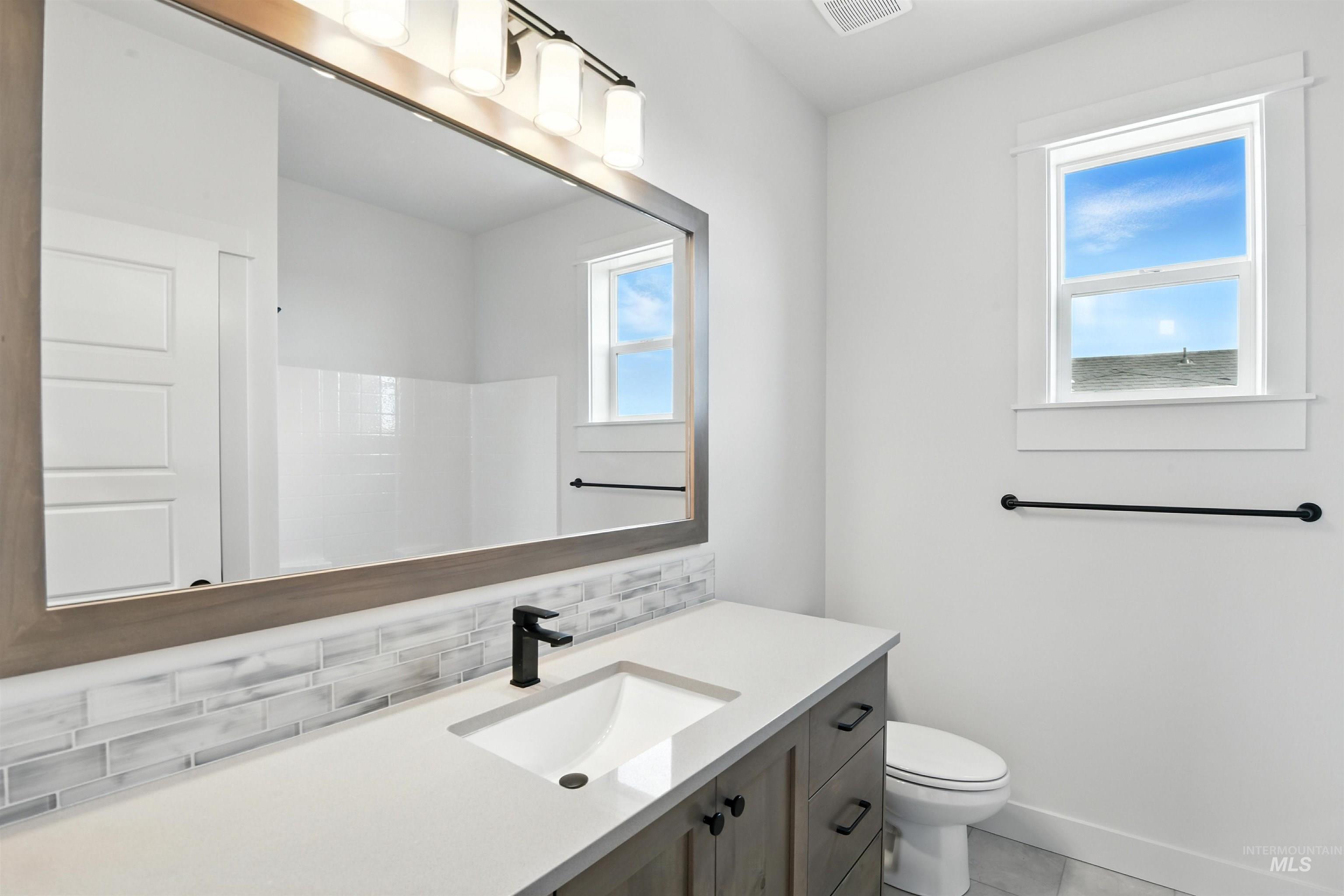 Full bath featuring decorative backsplash, vanity, and tile patterned floors