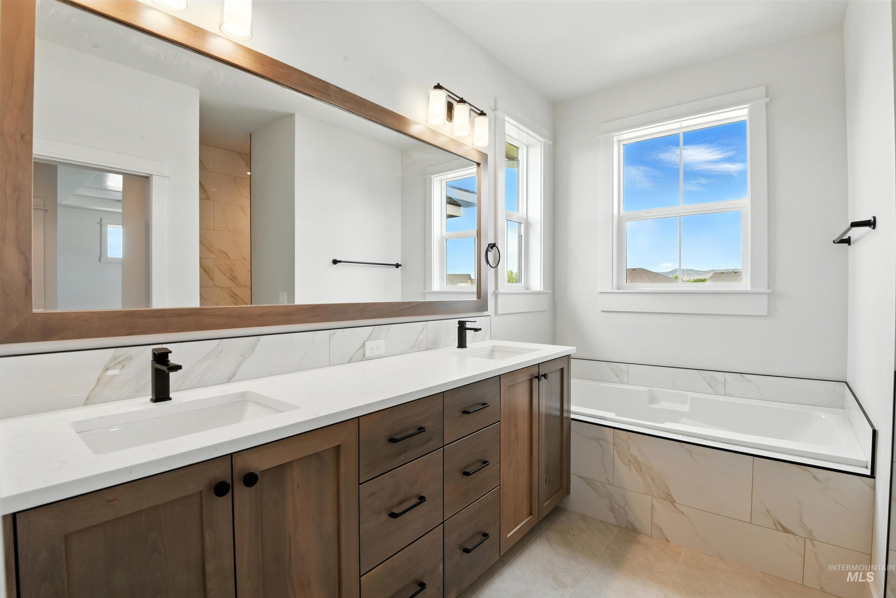 Full bath featuring double vanity and a garden tub