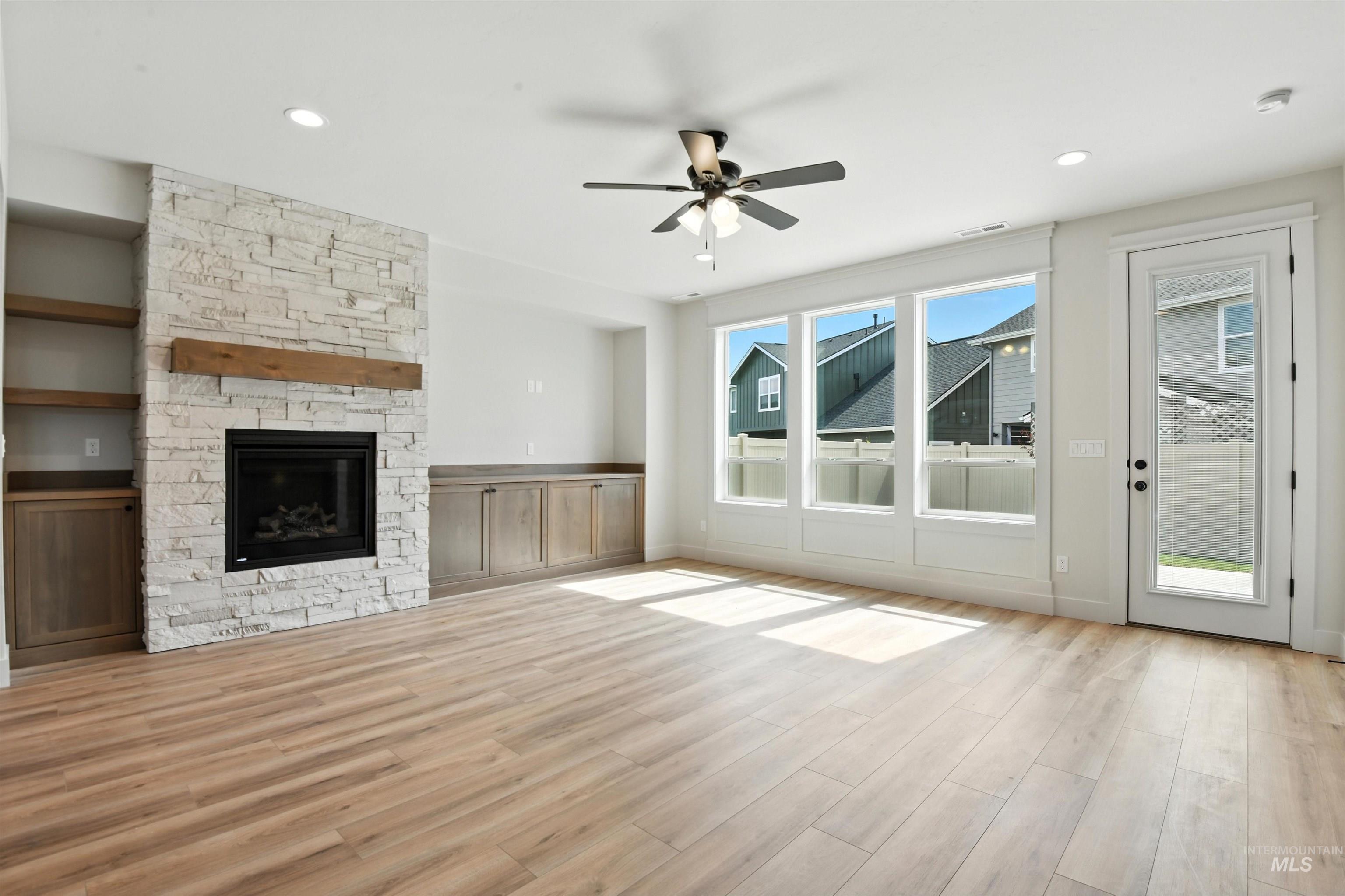 Unfurnished living room featuring ceiling fan, wood finished floors, a stone fireplace, and recessed lighting