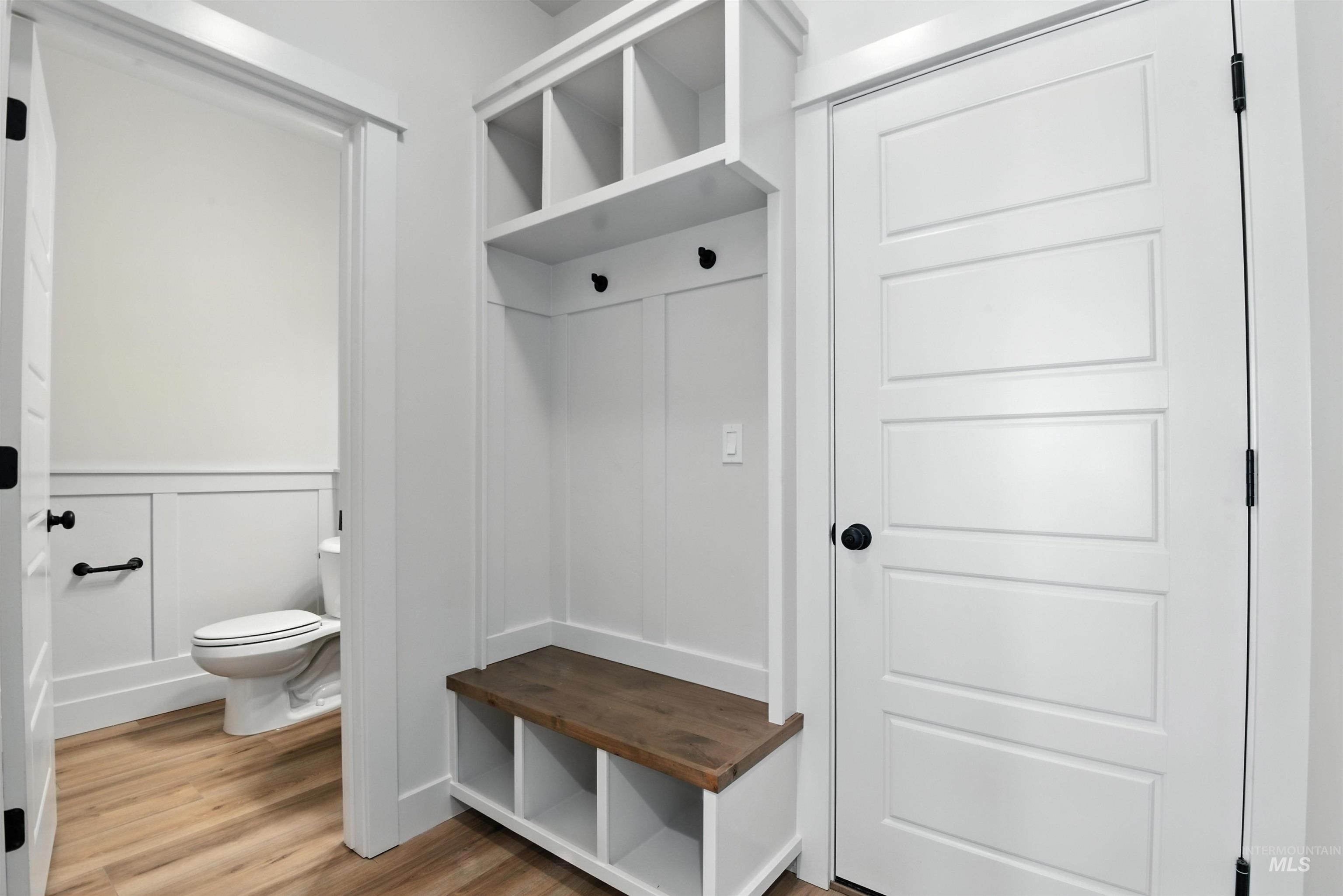 Mudroom with a decorative wall, light wood-style flooring, and wainscoting