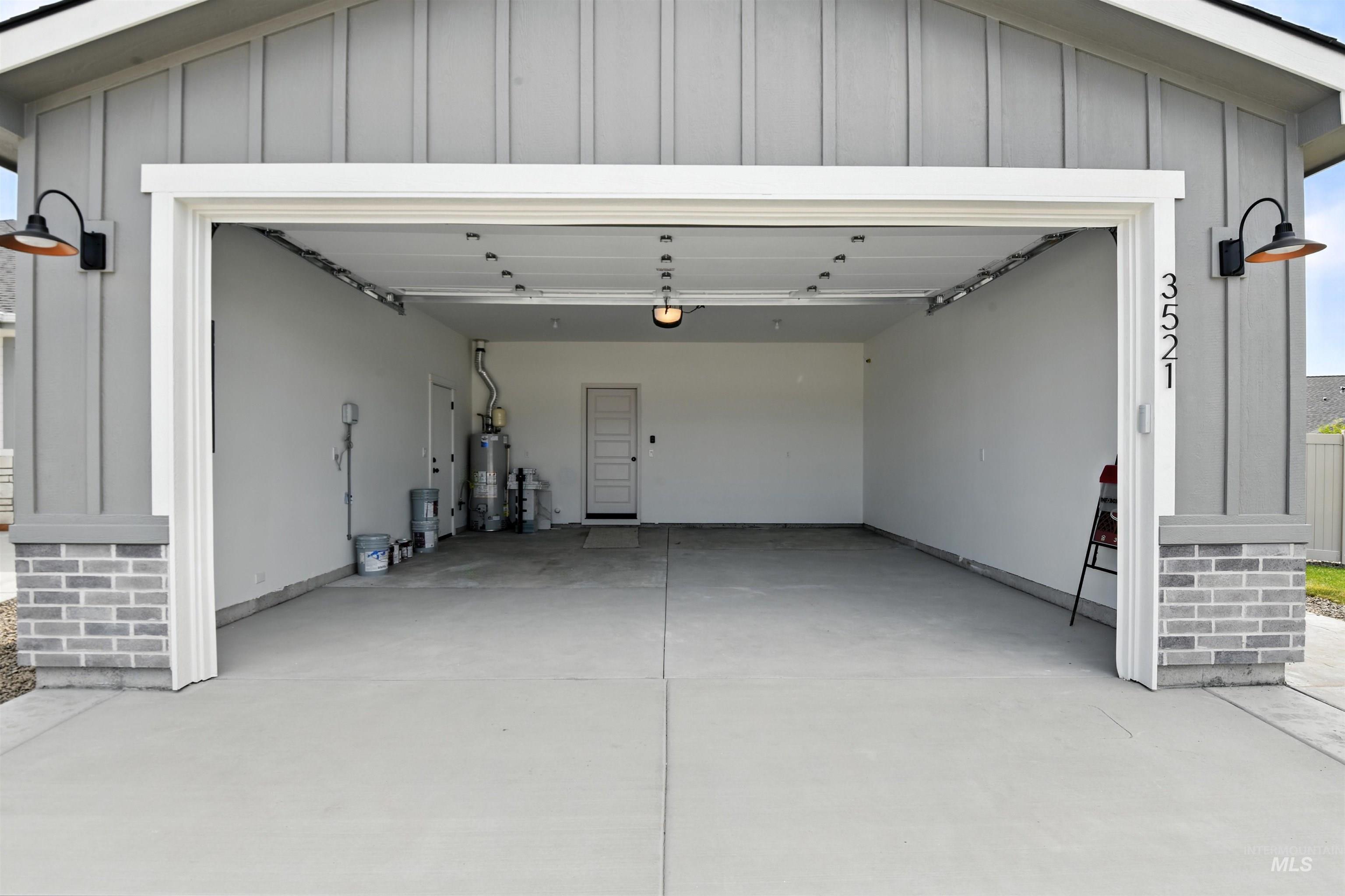Garage with gas water heater, concrete driveway, and a garage door opener