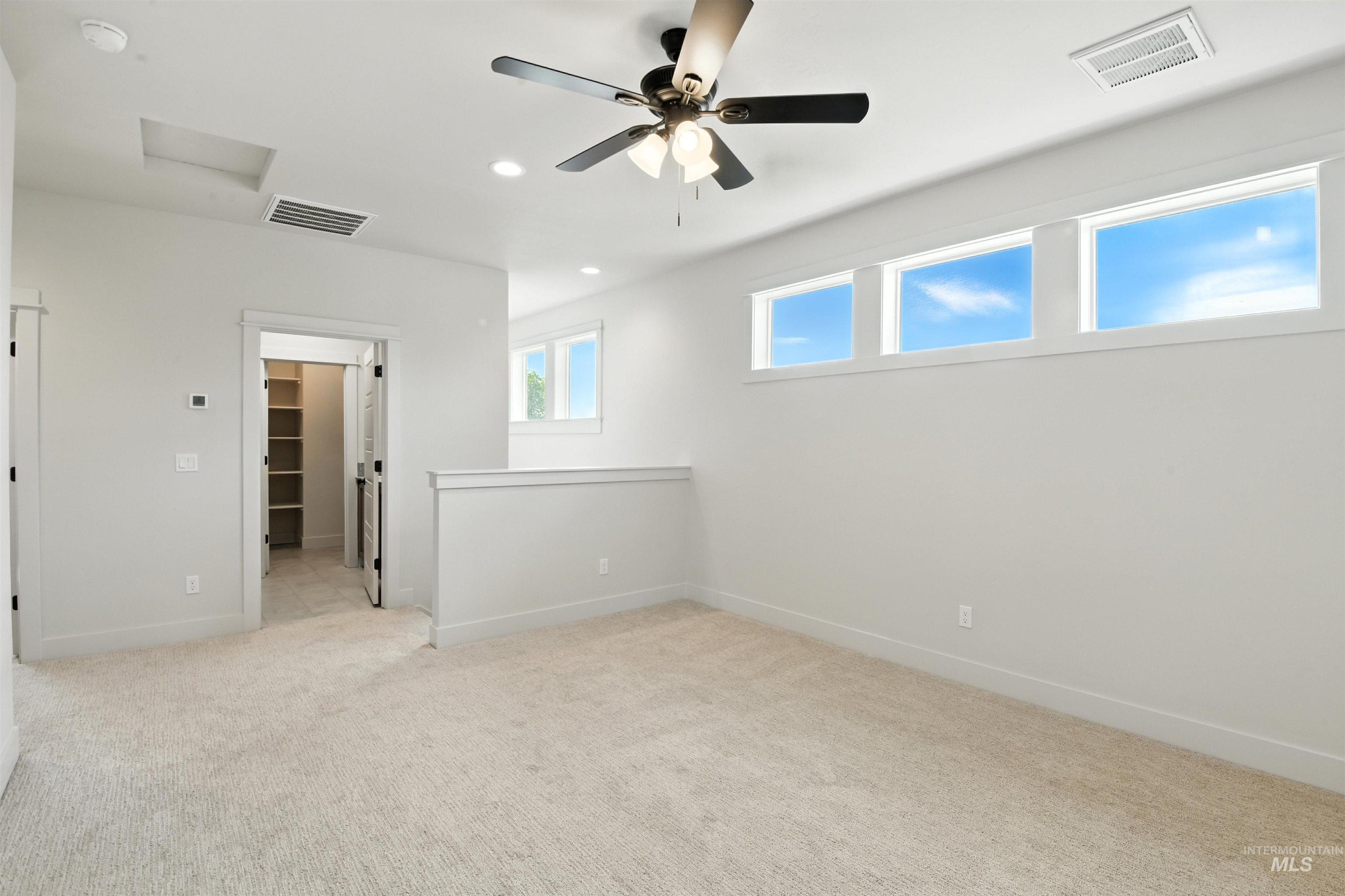 Unfurnished bedroom featuring a spacious closet, carpet, recessed lighting, attic access, and a ceiling fan